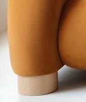 PAVIO sofa S4 – detail valcovitej nohy z masívneho dreva pod oblou podrúčkou.