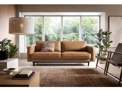 Rozkladacia pohovka LUXERA SOFA v hnedom čalúnení v modernom interiéri obývačky, nízke čierne nožičky a rovné podrúčky, pohľad spredu.