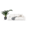 Pohovka LEO SOFA 3 (1BL + 1 + 1BP) na bielom pozadí v krémovej farbe, trojmiestna pohovka s dekou a rastlinou, pohľad z uhla.